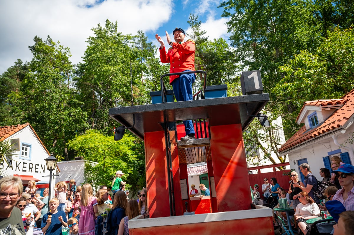 Dyreparken Kardemomme By. Politimester Bastian klapper mens han står oppe på trikken i sola.